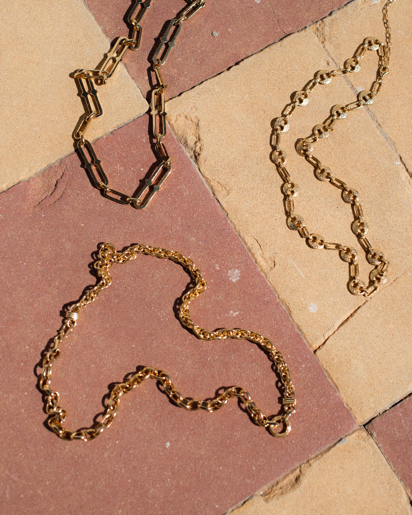 3 gold chain necklaces laid out on tiles