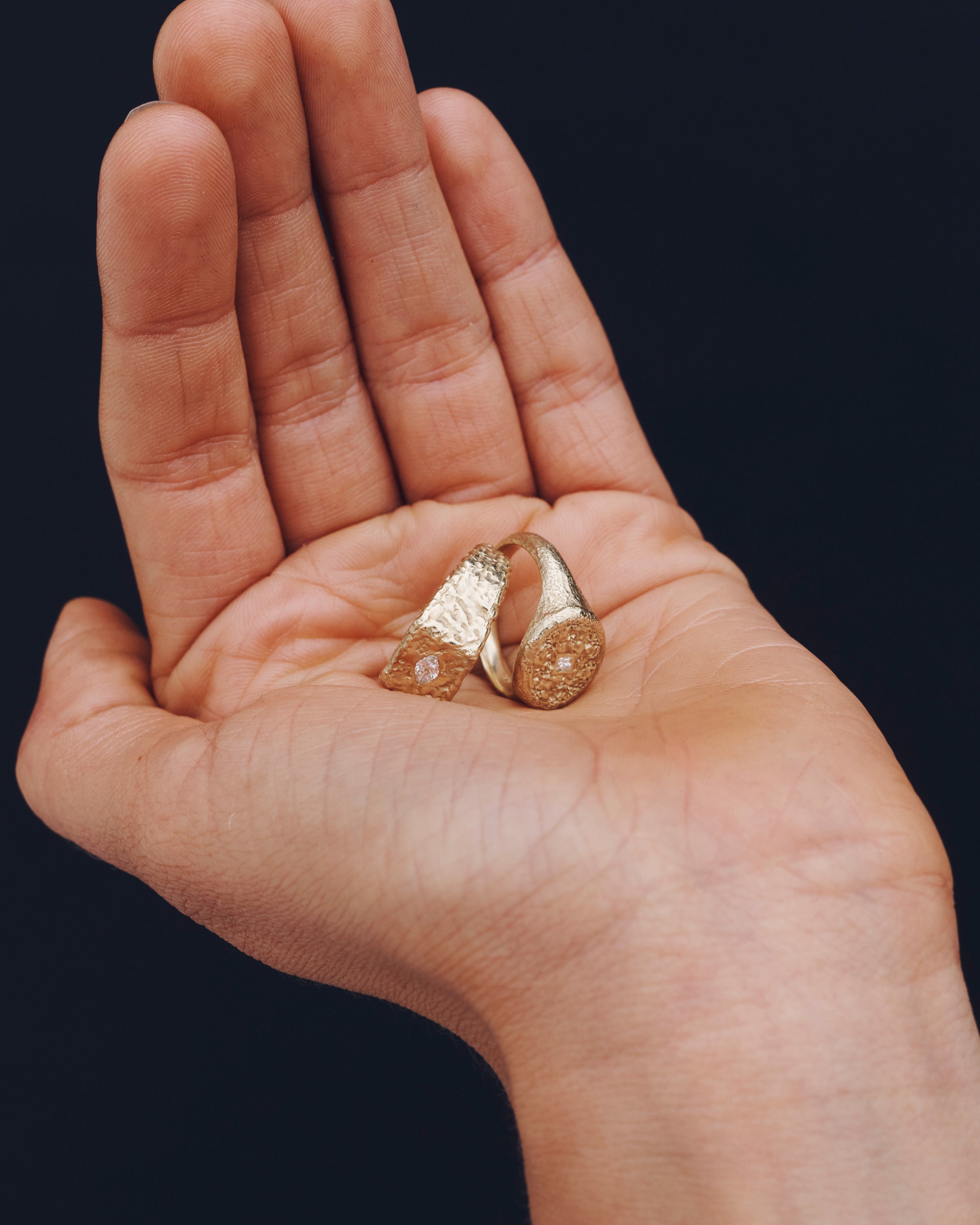 Hand holding two gold bars against a black background