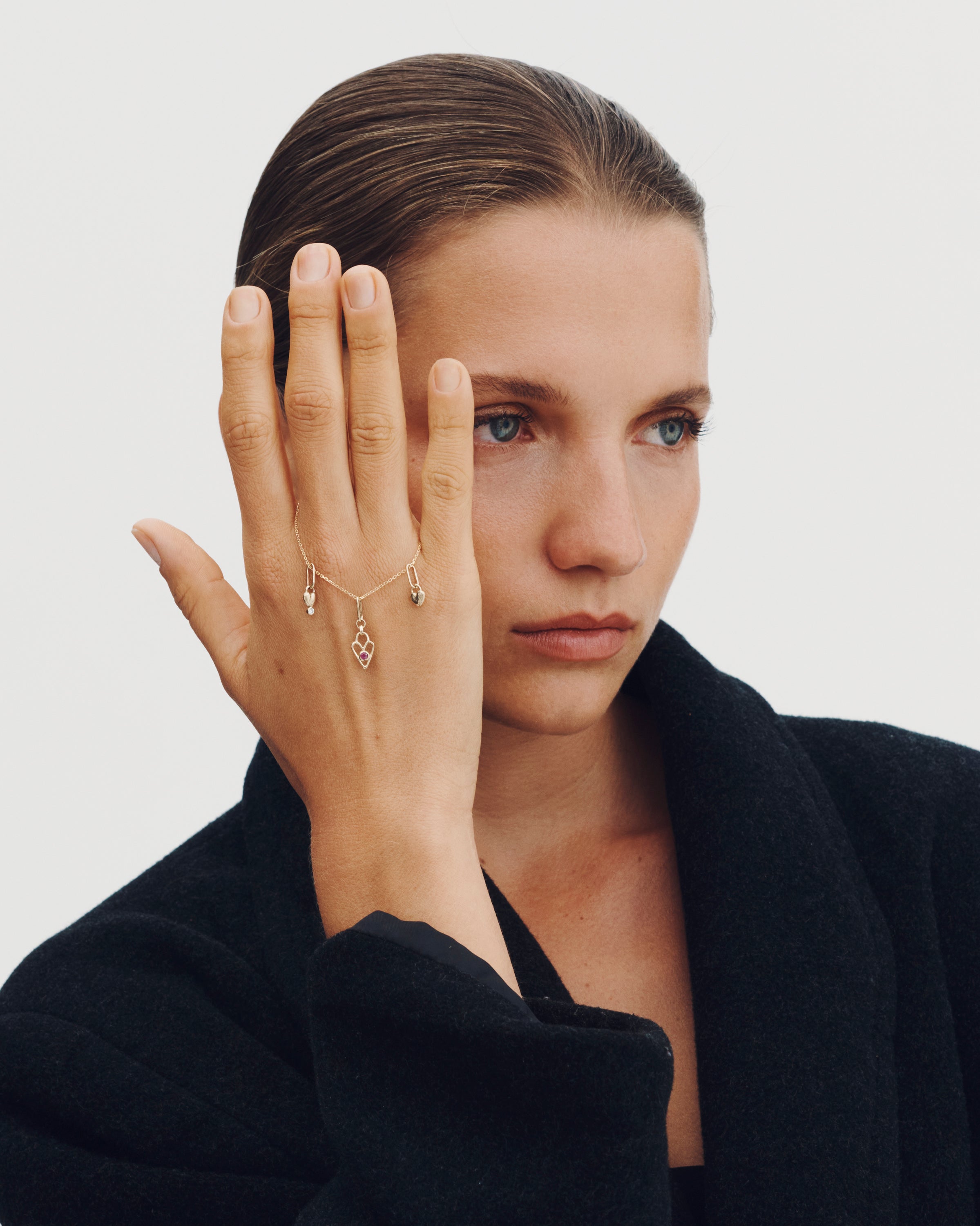 Woman wearing a delicate necklace with a plain background
