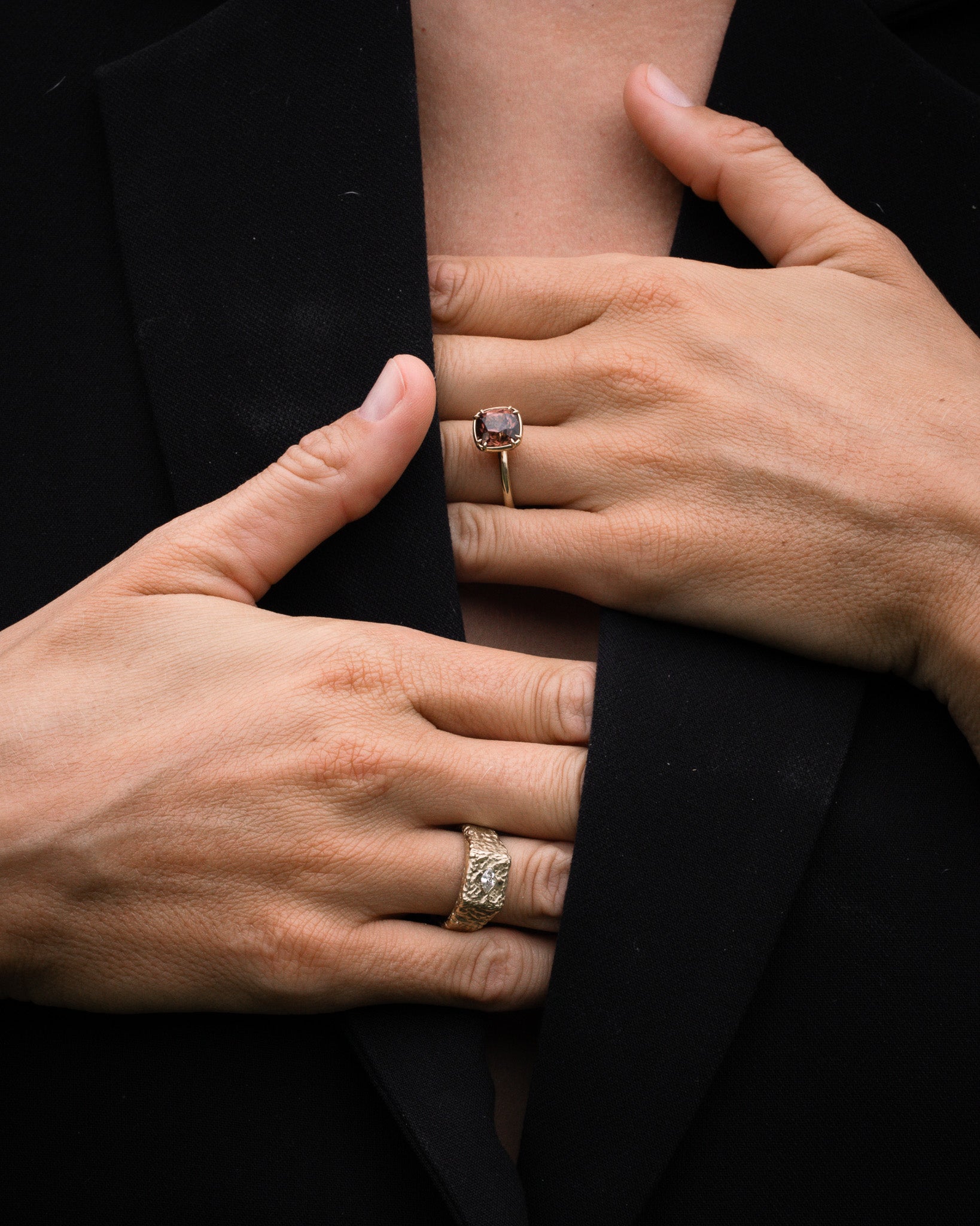 Close-up of two hands wearing rings on a black background