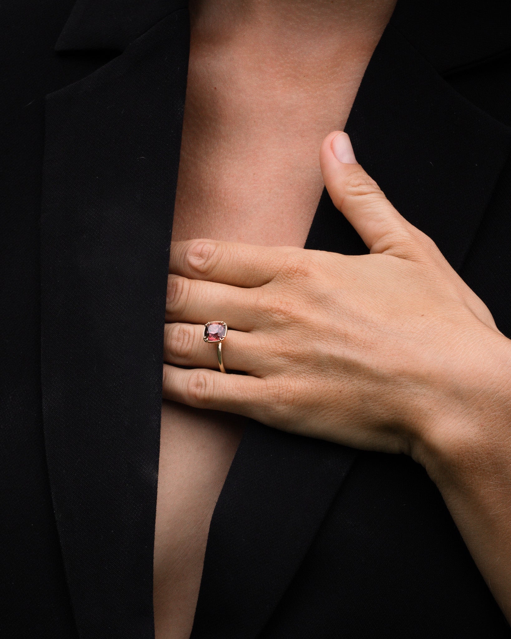Hand wearing a pink ring on a black background
