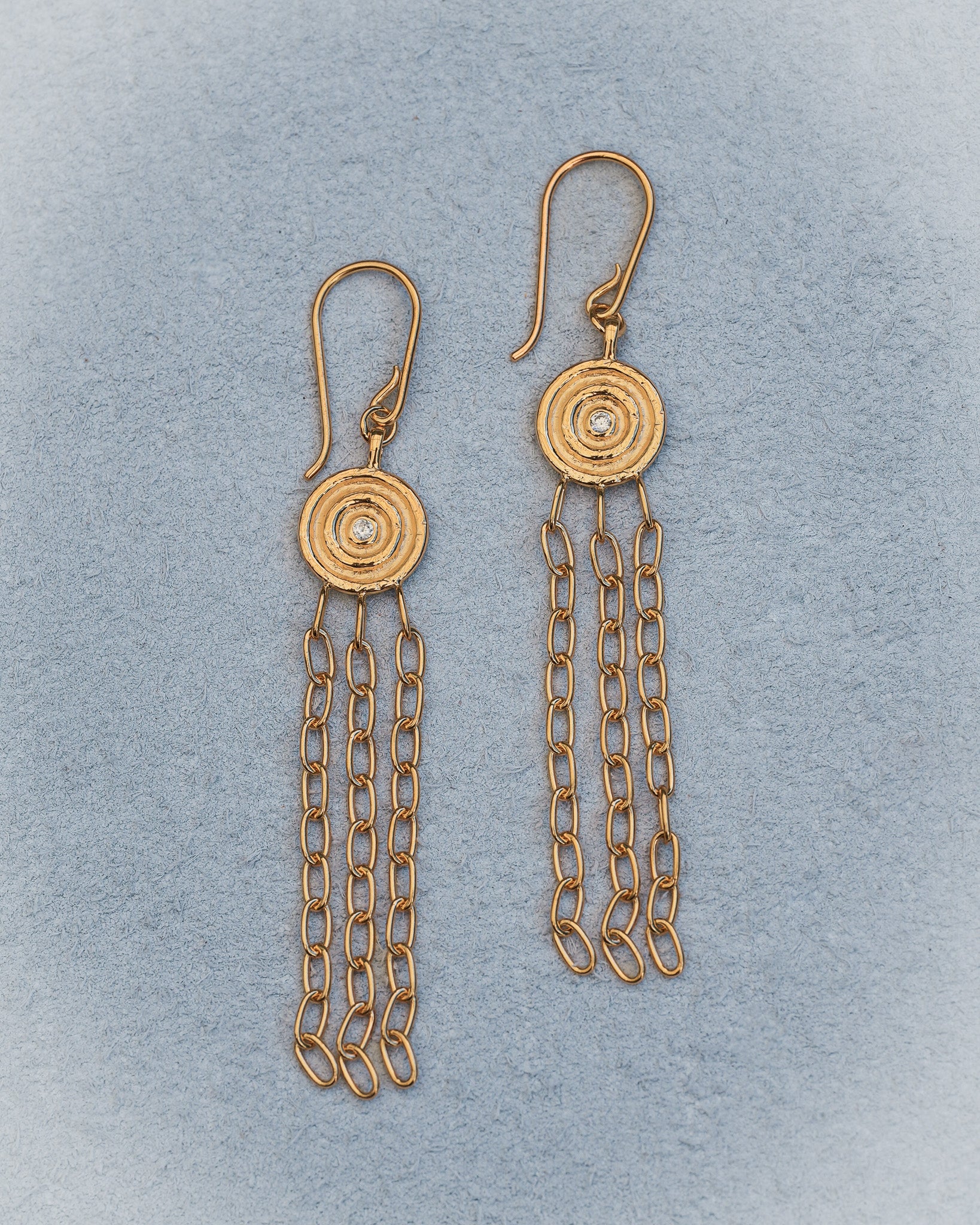 Gold chain earrings on a light blue background