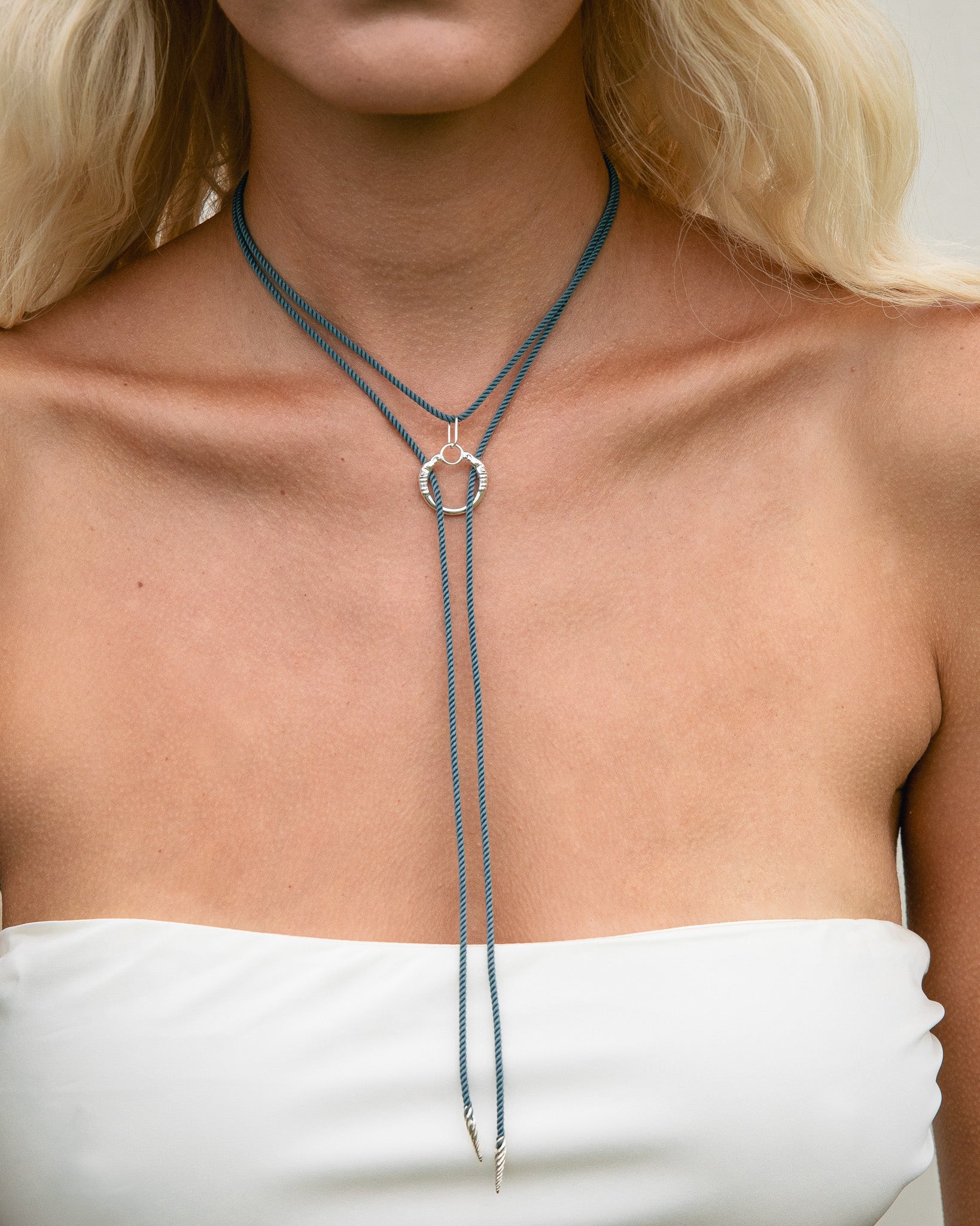 Close-up of a necklace on a person wearing a white top