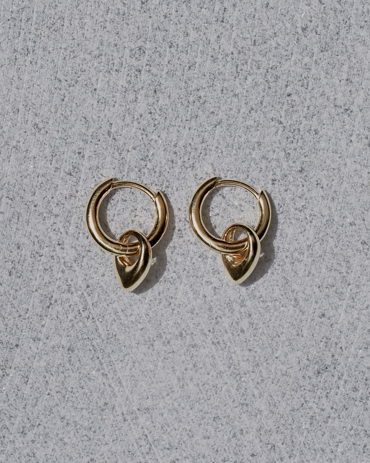 Pair of gold hoop earrings on a gray surface