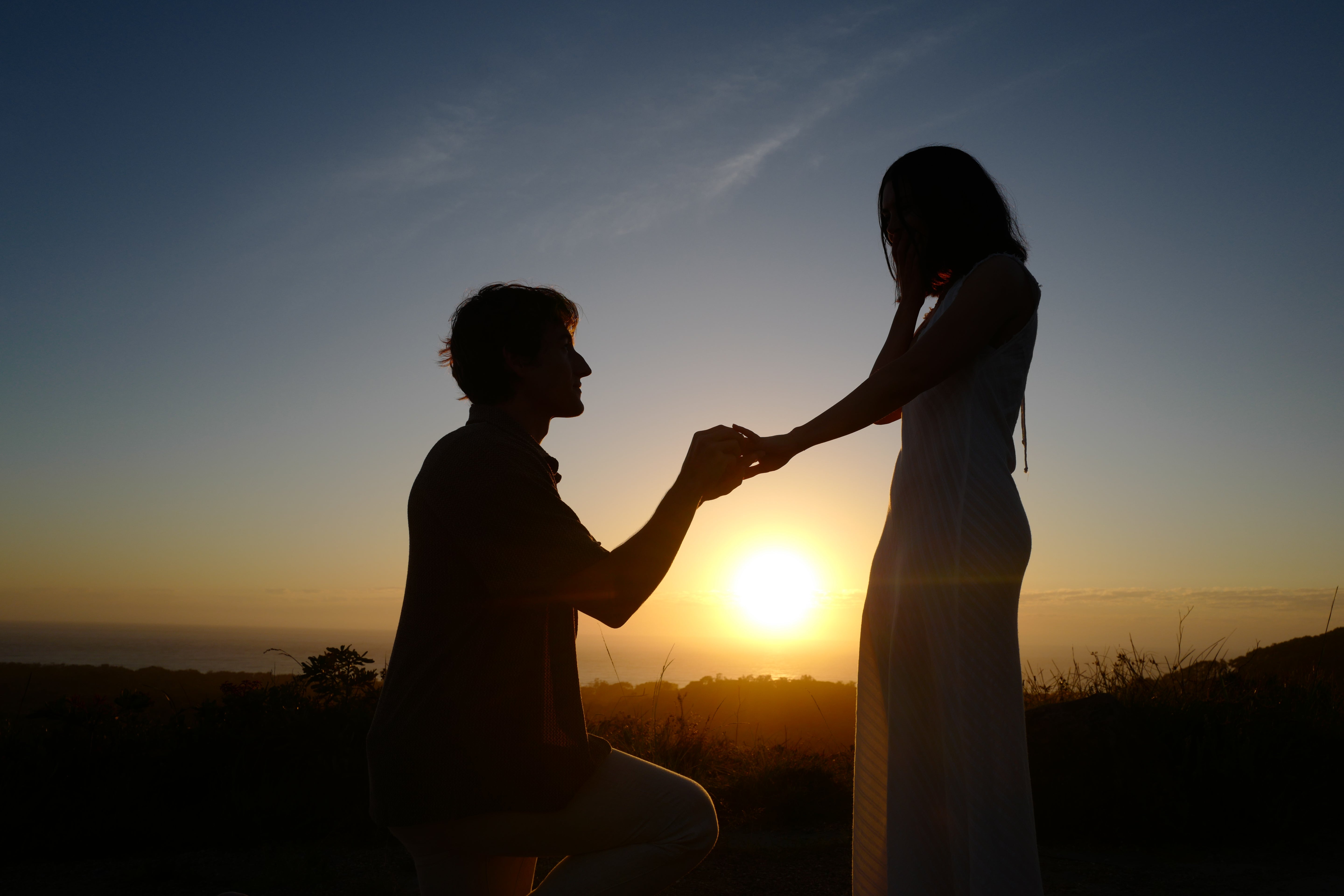 Silhouette of a couple holding hands against a sunset sky
