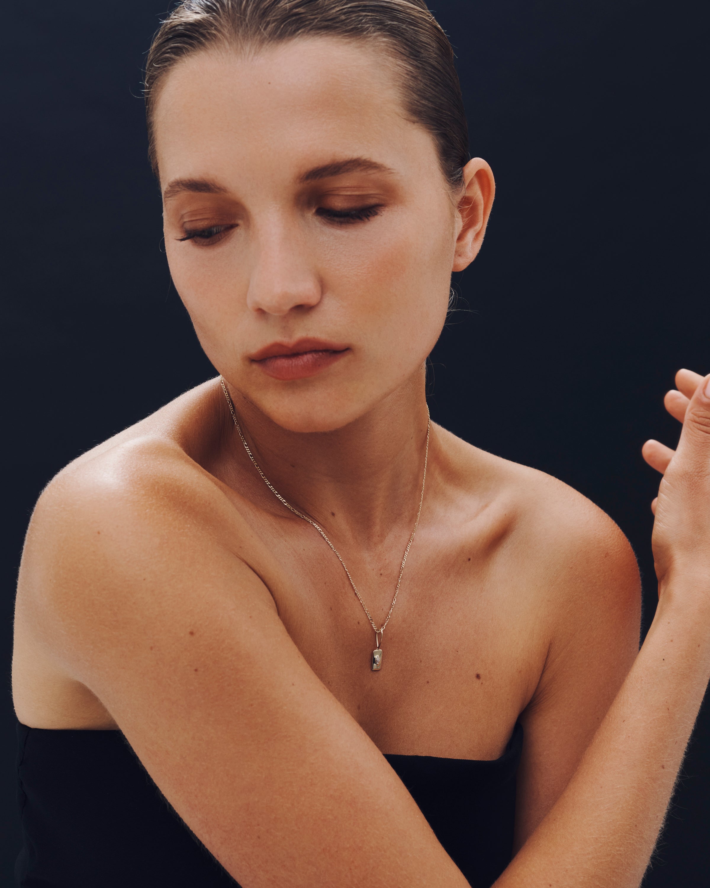 Woman wearing a delicate necklace against a dark background