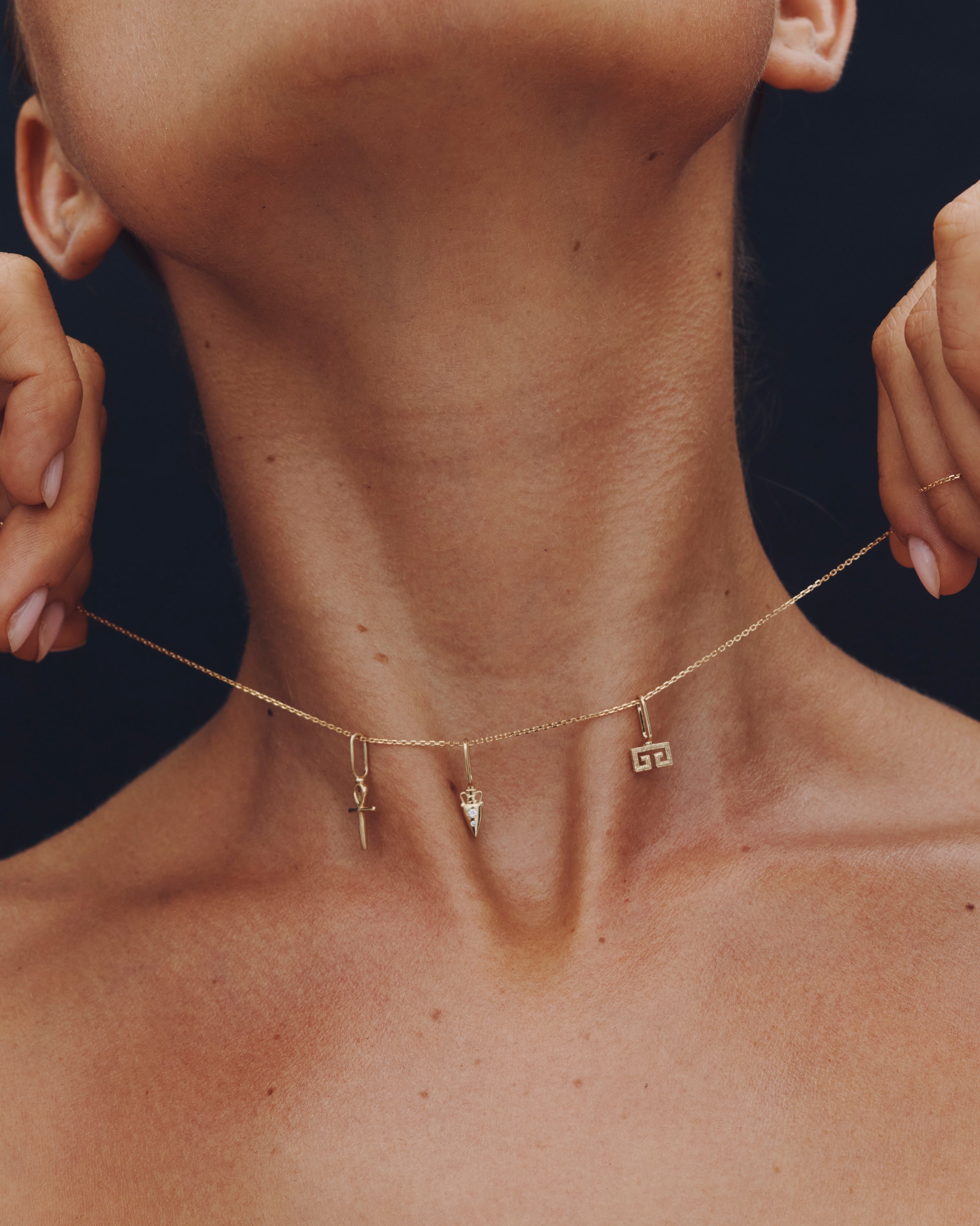 Necklace with three pendants on a person against a dark background