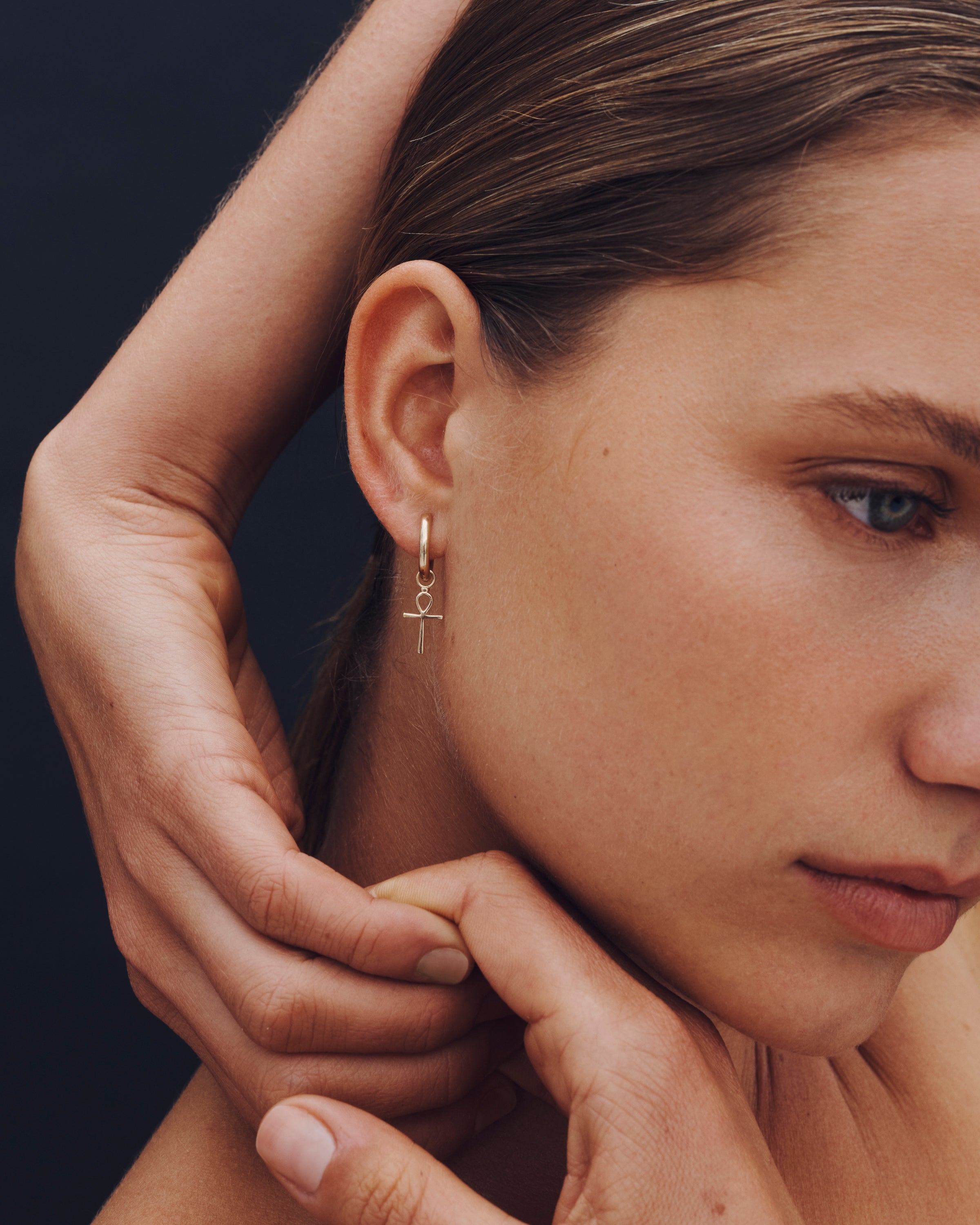 Close-up of a woman wearing a gold earring with a dark background