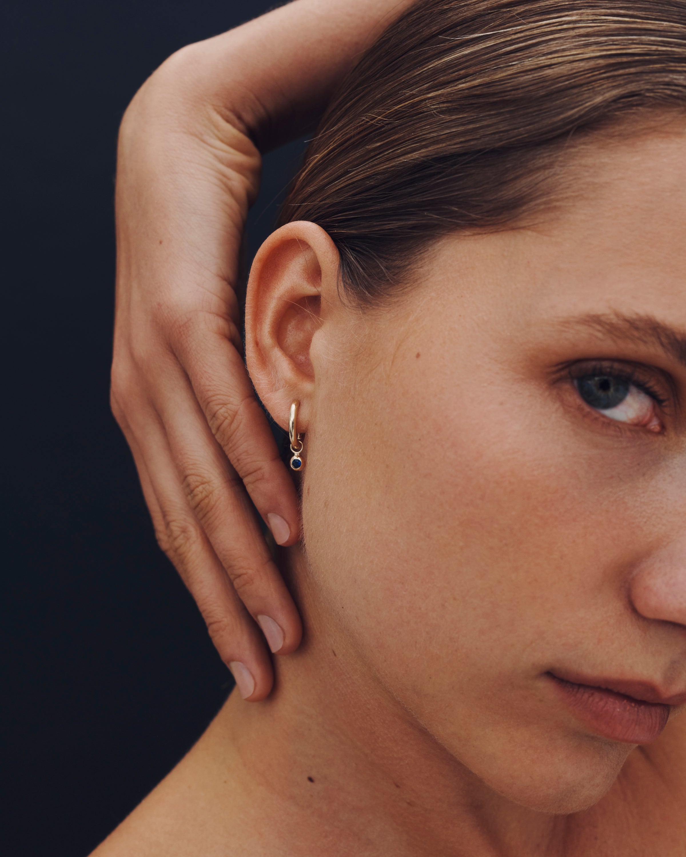 Close-up of a woman wearing an earring with a dark background