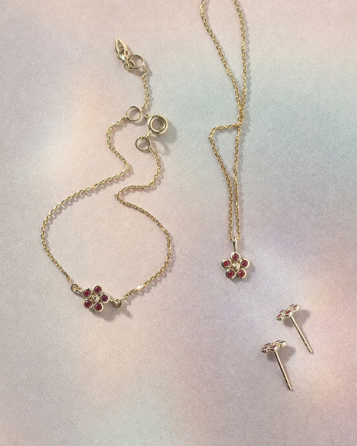 Daisy Ruby Necklace, Earrings and Bracelet in solid gold, flatlay