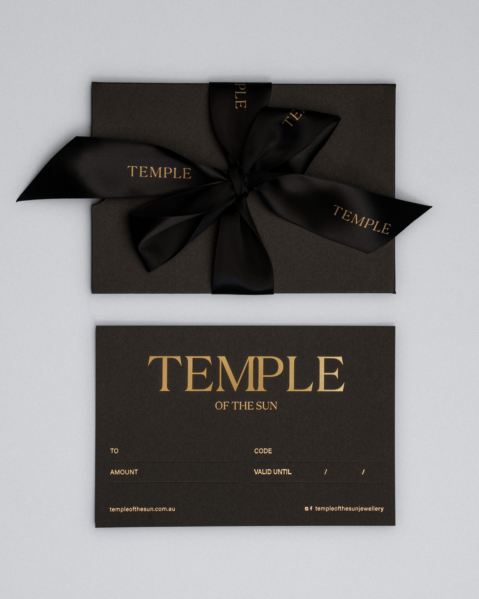 Black gift box with a black ribbon and 'Temple of the Sun' branding on a light gray background.