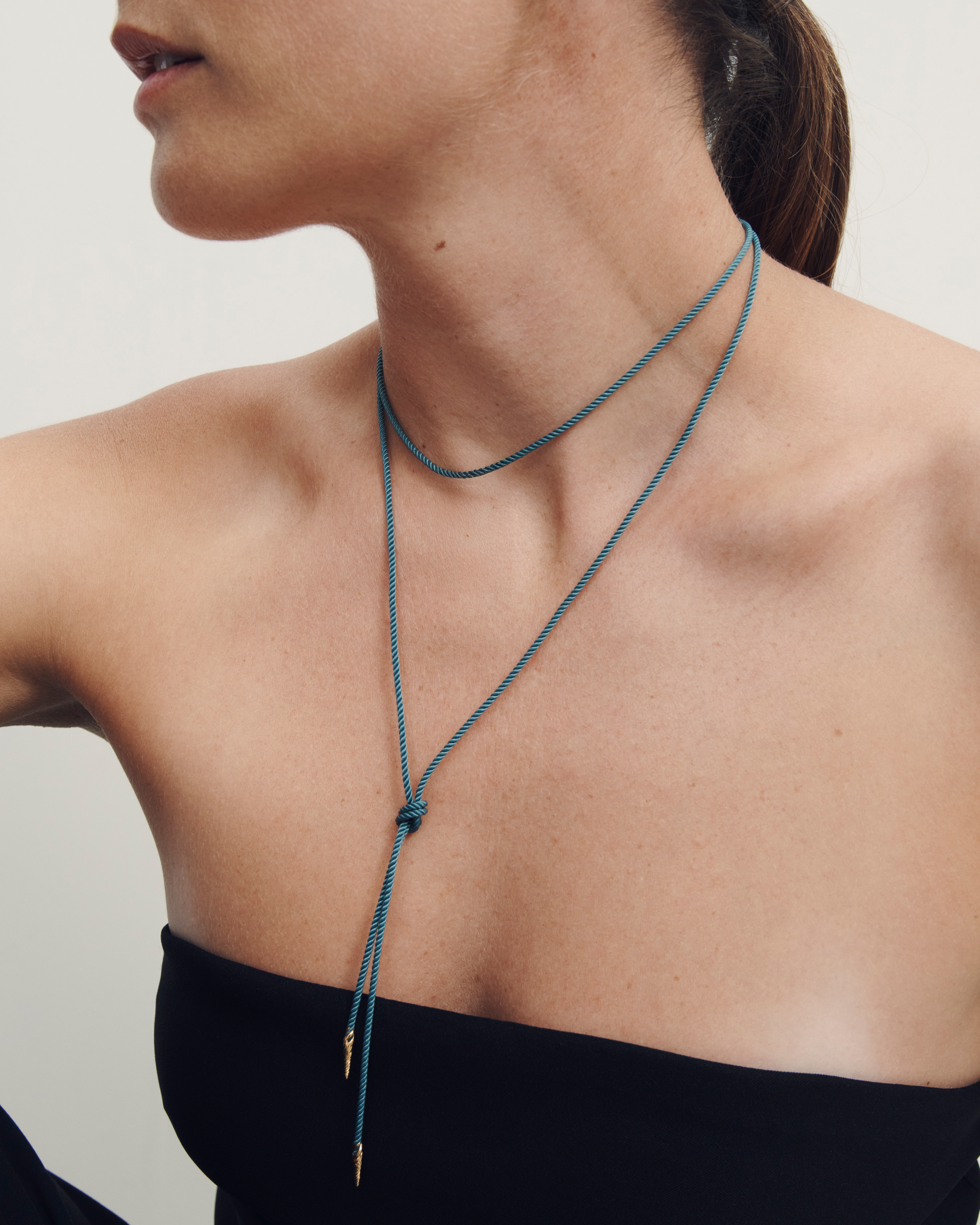 Woman wearing a blue necklace with a minimal background