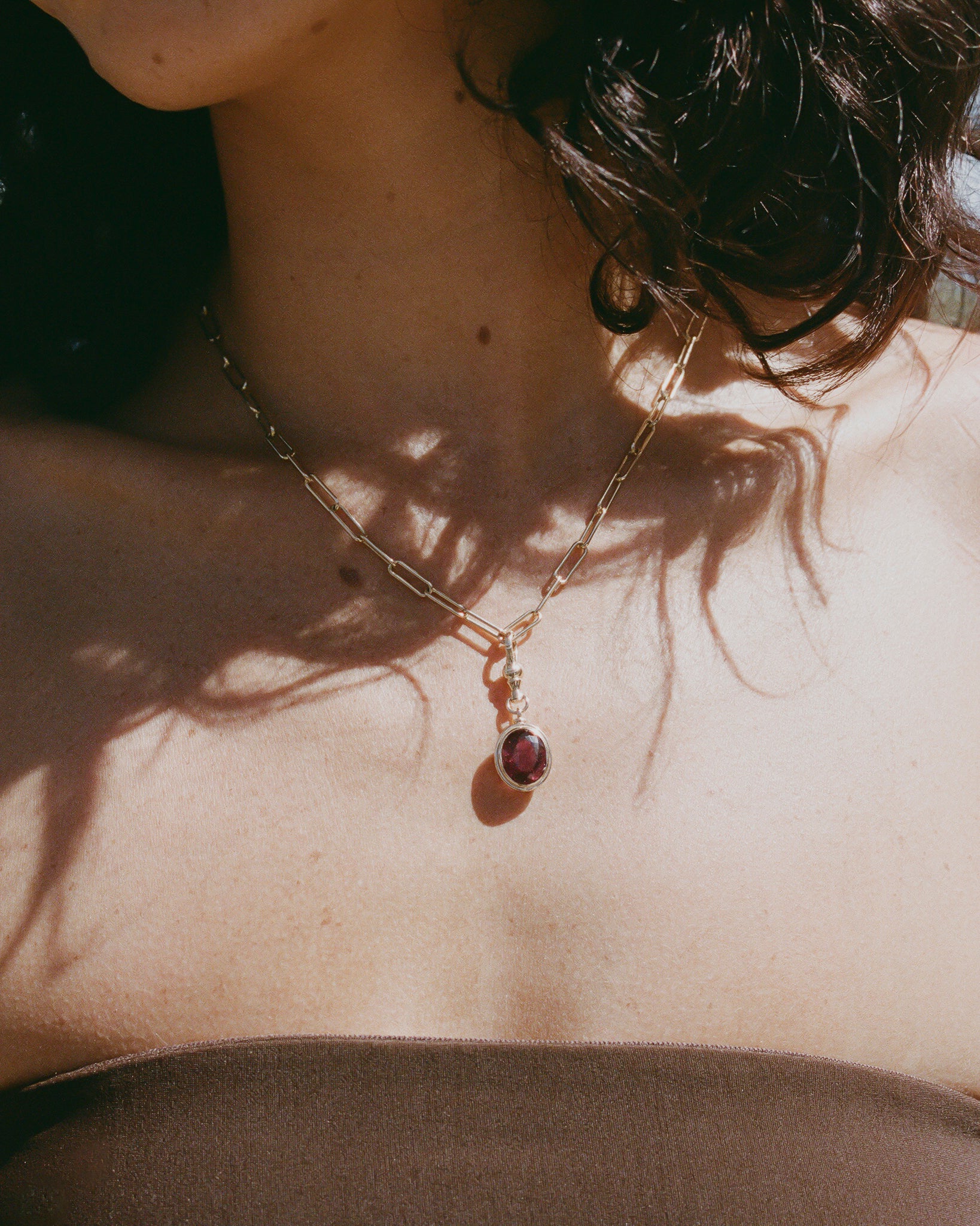 Necklace with a pendant on a person's neck, casting a shadow.