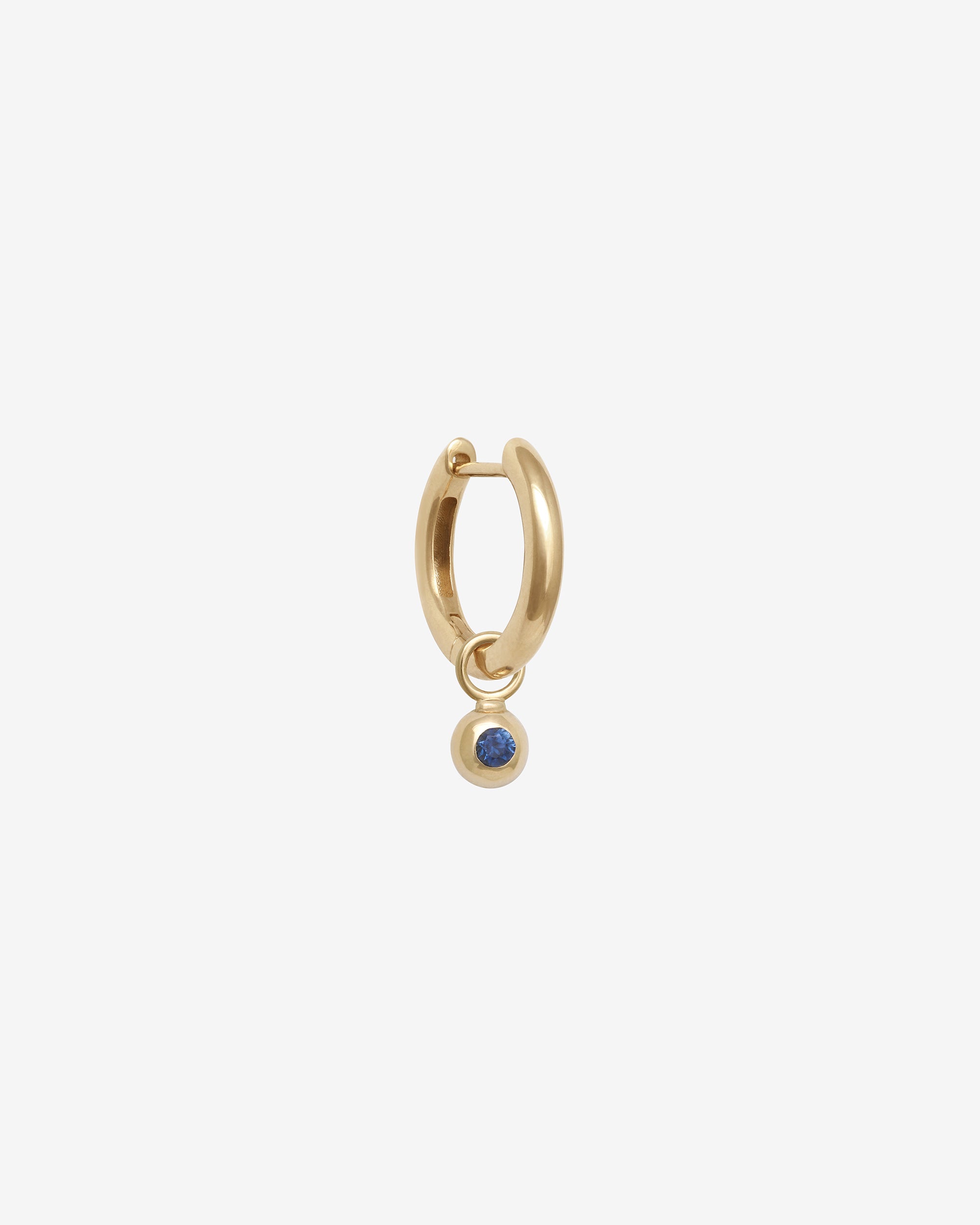 Gold hoop earring with a small blue gemstone on a white background