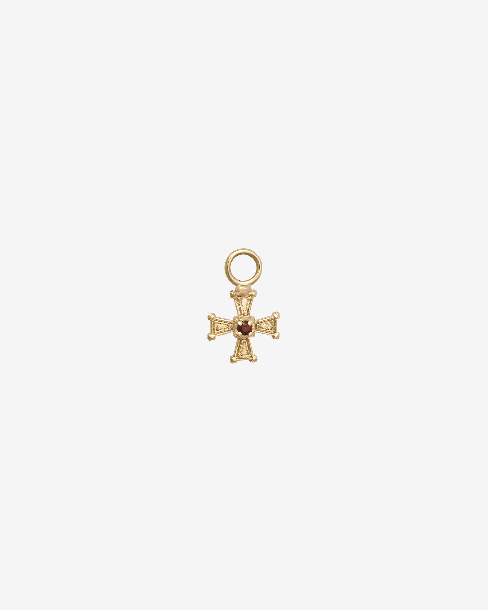 Gold cross pendant with a small gemstone on a white background