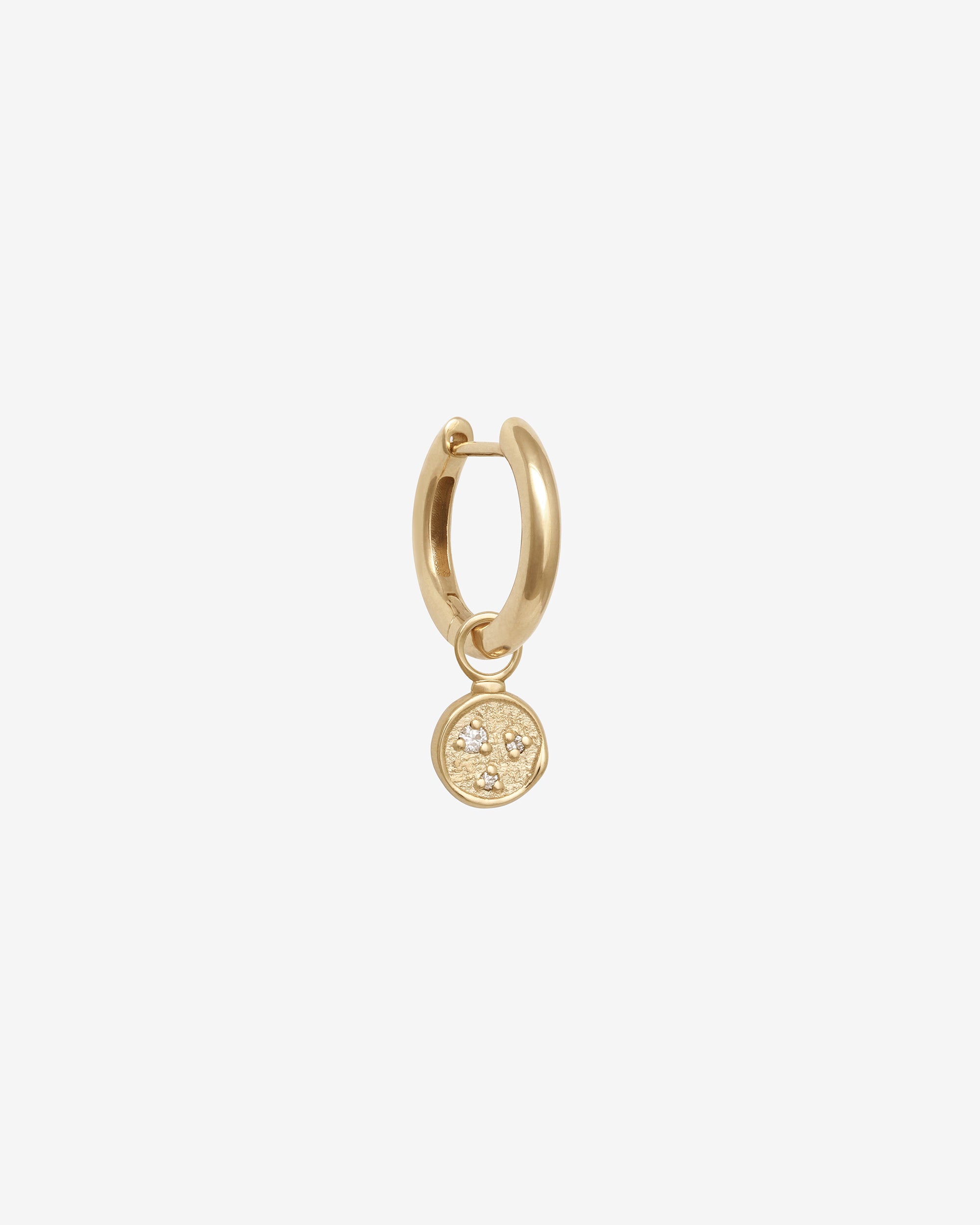 Gold hoop earring with a small round pendant on a white background