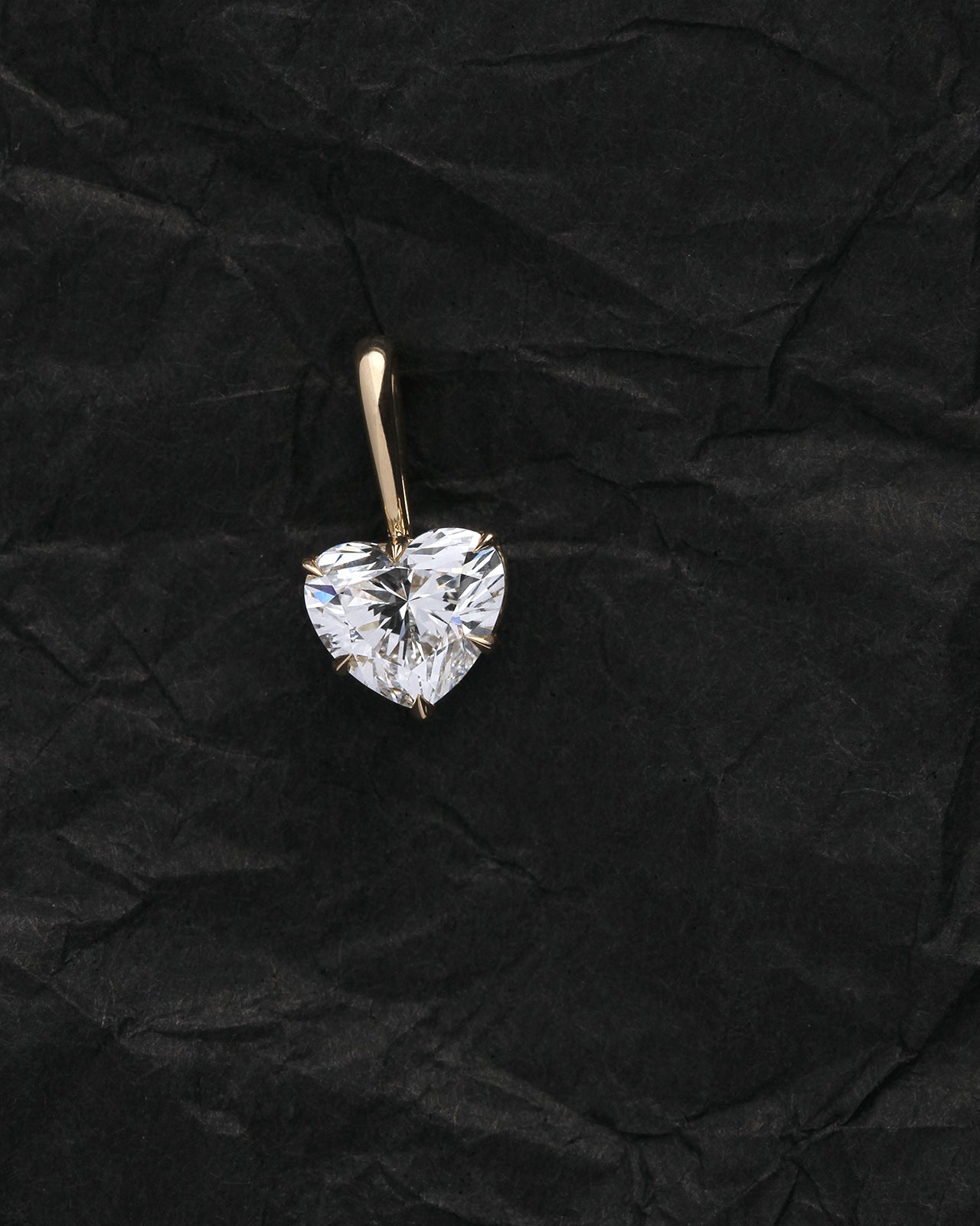 Heart-shaped diamond pendant on a black textured background