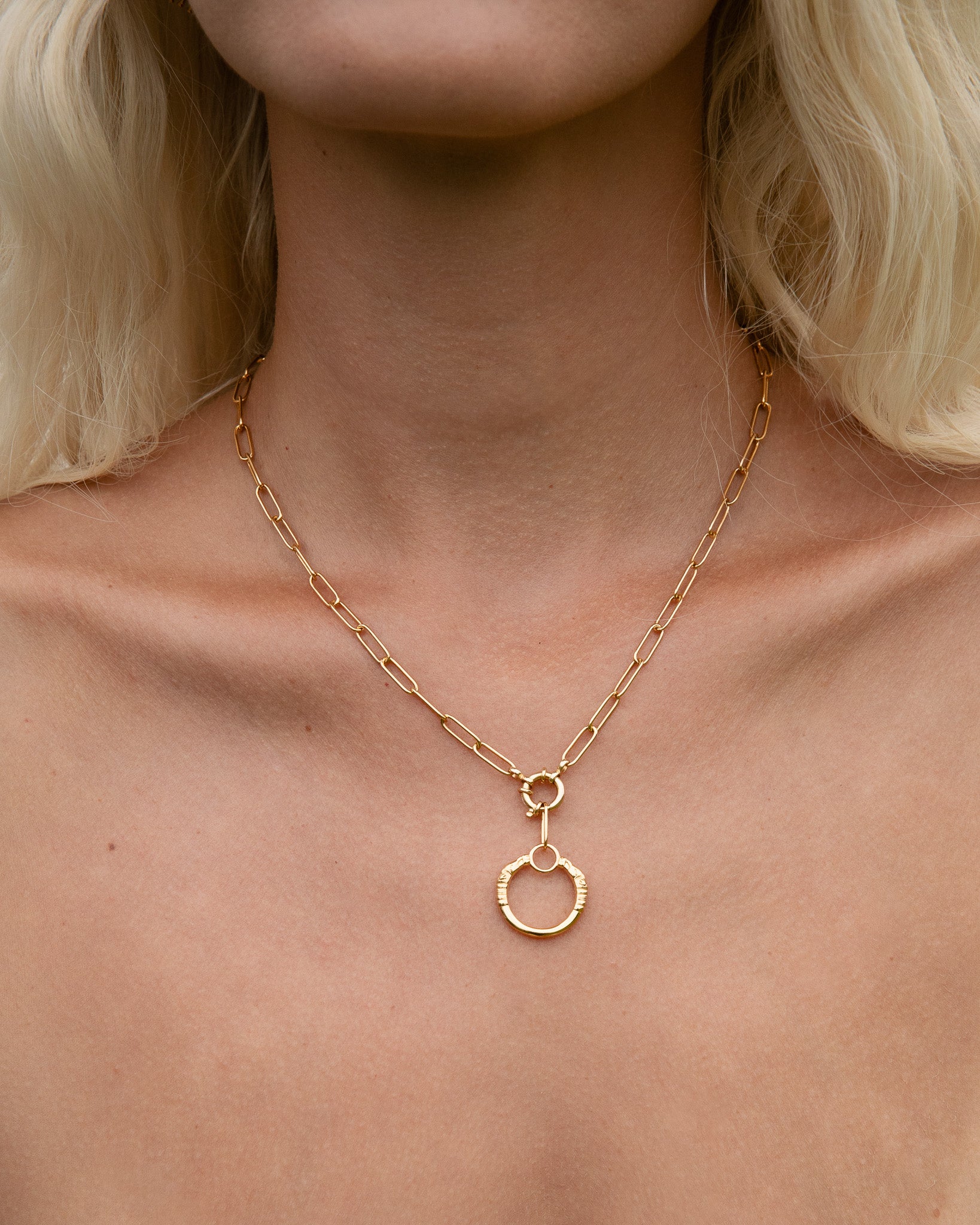 Gold necklace with a small pendant on a person's neck